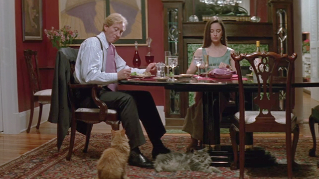 China Moon - Rupert Charles Dance and Rachel Madeleine Stowe sitting at dinner table with long-haired tabby cats on floor