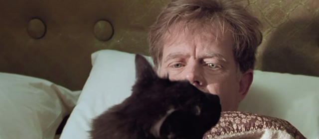 The Cooler - Bernie William H. Macy looking at long haired black cat Trixie sitting on his chest in bed