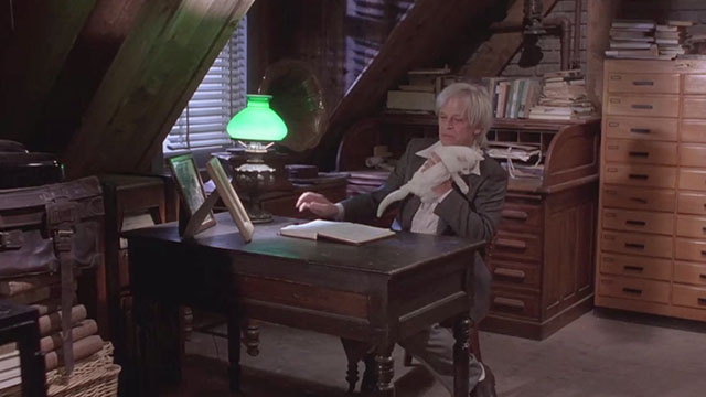 Crawlspace - Gunther Klaus Kinski holding white kitten while sitting at desk