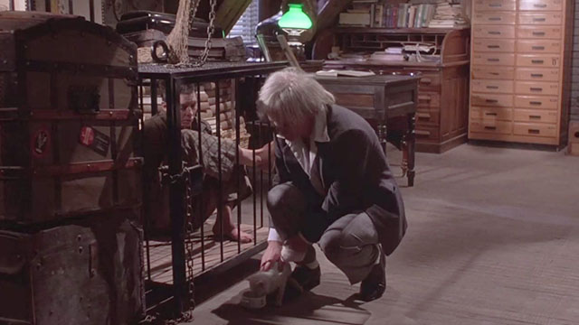 Crawlspace - Gunther Klaus Kinski setting white kitten on floor with bowl of milk next to cage with Sally Brown