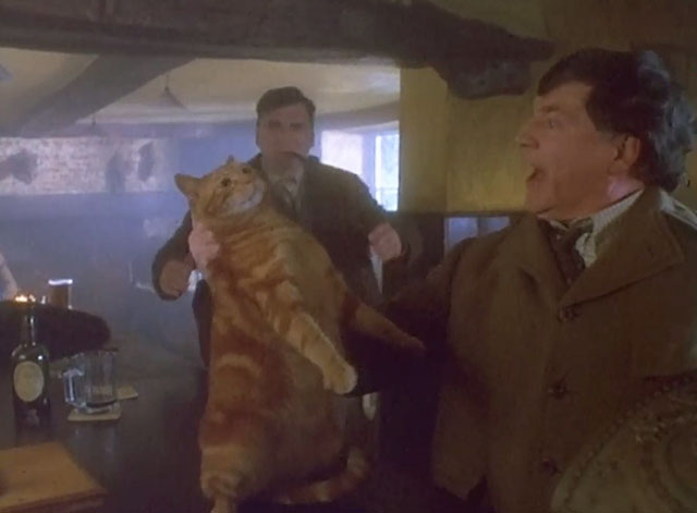 Grotesque - Sir Hugo Coal Alan Bates holding ginger tabby cat by scruff on bar as George Jim Carter approaches