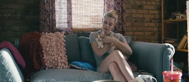 Hustlers - Annabelle Lili Reinhart on couch holding orange and white tabby cat