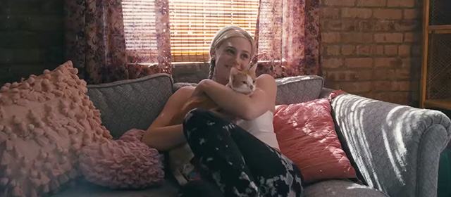 Hustlers - Annabelle Lili Reinhart on couch holding orange and white tabby cat