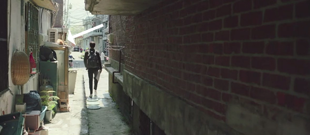 Parasite - Ki-woo Woo-sik Choi walking away in alley with orange and white cat sleeping nearby