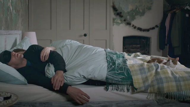 Surviving Christmas - Dan Julian Ovenden sleeping in bed with ginger and white tabby cat Poppy at his feet