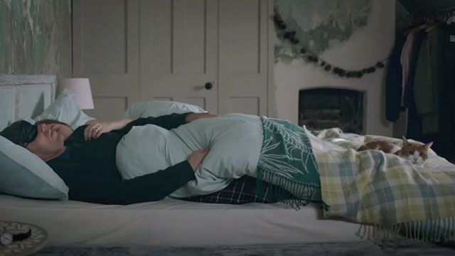 Surviving Christmas - Dan Julian Ovenden sleeping in bed with ginger and white tabby cat Poppy at his feet