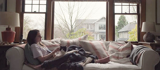 The Unforgivable - Katie Aisling Franciosi lying on couch with tuxedo cat