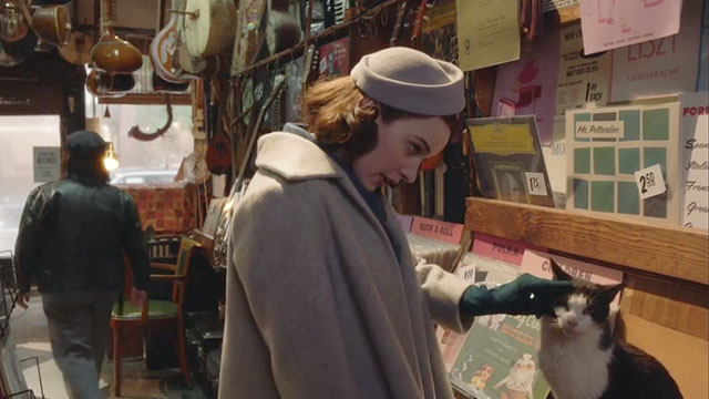 The Marvelous Mrs. Maisel - The Disappointment of the Dionne Quintuplets - Rachel Brosnahan and Susie Alex Borstein looking at albums in The Music Inn with tuxedo cat